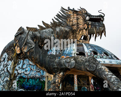 Riesig und unheimlich stone Dragon mit Spikes und offener Mund mit Zähnen von unten im Weitwinkel an verlassenen Water Park, Thuy Tien See, Hue, Vietnam Stockfoto