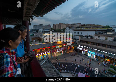 Xian, China - Juli 2019: Chinesisch ältere Touristen beobachten die belebten Straßen von das Muslimische Viertel am Abend aus der Sicht Balkon in Dr Stockfoto