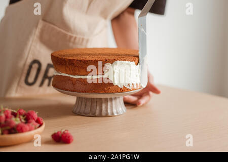 Pastry Chef setzt die Sahne auf dem Kuchen. Prozess kochen Biskuitteig. Stockfoto