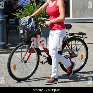 Junge Frau geht auf der Straße mit dem Fahrrad Stockfoto