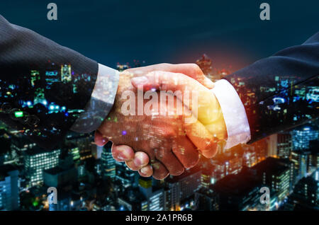 Partnerschaft. Zwei business Mann Investor zitternden Hand nach Projektbesprechung mit bei Sonnenaufgang und modernen Stadtbild Hintergrund, business Handshake Stockfoto