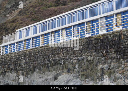 Umkleidekabinen am Strand hinter einem Stein Sea Wall. Die hl. Agnes, North Cornwall, UK. Stockfoto