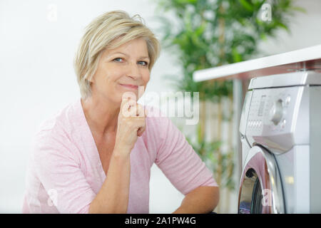 Ältere Frau laden Waschmaschine zu Hause Stockfoto