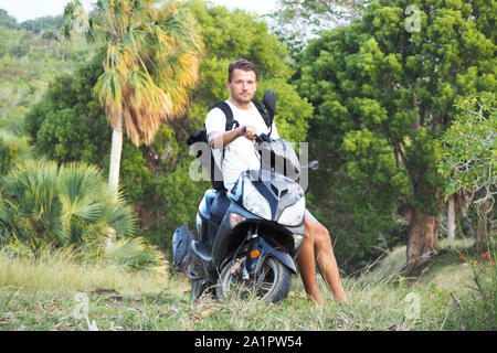 Ein Mann sitzt auf einem Motorroller in der Natur. Dominikanische Republik. Stockfoto