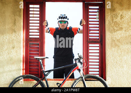 Radfahrer Porträt in einem alten, verlassenen Haus. Er sieht aus dem Fenster. Stockfoto