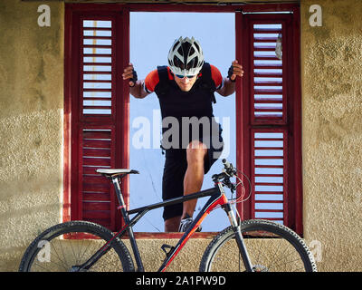 Radfahrer Porträt in einem alten, verlassenen Haus. Er sieht aus dem Fenster. Stockfoto