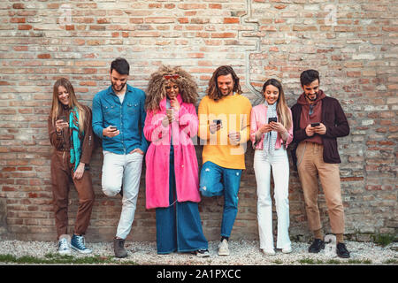 Multirassischen Freunden über Smartphone gegen eine alte Mauer - junge Leute, die von mobilen Smart Phone süchtig-Technologie Konzept mit immer verbunden. Stockfoto