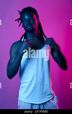Attraktive afro Mann Werbung ein weißes Hemd, bis Foto schliessen. Isolierte violette Hintergrund, studio Shot, Stockfoto
