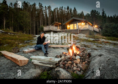 Frau liest, Lagerfeuer in Norwegen Stockfoto
