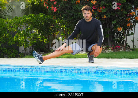 Mann zu tun stretching Übung durch den Pool. Stockfoto