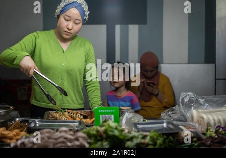 Xian, China - August 2019: muslimische Frau Snacks verkaufen auf dem Food Street im muslimischen Viertel Stockfoto