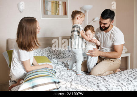 Junge Eltern lehren ihre älteste Tochter kümmern, kümmern sich um Ihre kleine Schwester, bis Foto schliessen. glückliche Mutterschaft, Vaterschaft, Mutterschaft Stockfoto