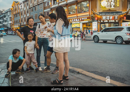 Landschaftspark Wulingyuan gelegen, China - August 2019: Chinesische Familie außerhalb Restaurant und berät über Menü Stockfoto