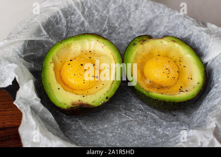 Die beiden Hälften des Avocado mit Eiern in der eiserne Pfanne. Zubereitung von gebackene Eier in Avocado Stockfoto