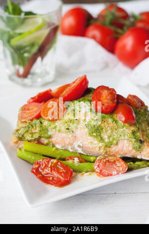 Lachs in Folie gebacken mit Pesto, Tomaten und Spargel. Leckeren, gesunden Seafood Dinner Stockfoto