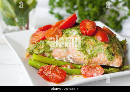 Lachs in Folie gebacken mit Pesto, Tomaten und Spargel. Leckeren, gesunden Seafood Dinner Stockfoto