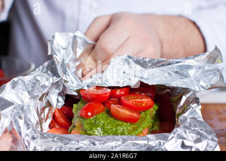 Zubereitung von Lachs in Folie gebacken mit Pesto, Tomaten und Spargel Stockfoto