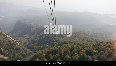 Blick auf die Berge von der Kabine mit der Seilbahn auf die Spitze des Tahtali und das Meer in der Nähe der Küste von Kemer, Antalya, Türkei Stockfoto