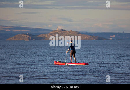 Portobello, Edinburgh, Schottland, Großbritannien. September 2019. Ein Mädchen auf Stand Up Paddle Board genießt 15 Grad und Sonnenschein auf dem Firth of Forth mit Inchkeith Island im Hintergrund. Stockfoto