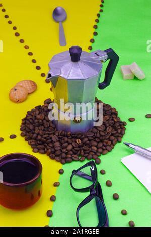 Objekte, die Kaffeepause mit kleinen traditionellen Italienischen Kaffeemaschine an grünen und gelben Hintergrund. Kaffeebohnen. Stockfoto