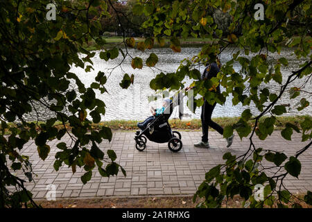 Mom Spaziergänge mit Kinderwagen am Ufer eines Teiches im Herbst Park in Moskau, Russland Stockfoto