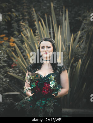 York, Großbritannien - 18 August 2019: eine Braut, die in einem schwarzen Kleid steht allein während einer Hochzeit im Freien Stockfoto