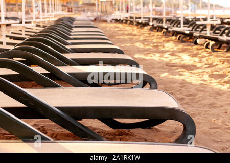 Liegestühle stehen in einer Linie am Strand in den Sand. Erholung und Urlaub. Sonnigen morgen Stockfoto