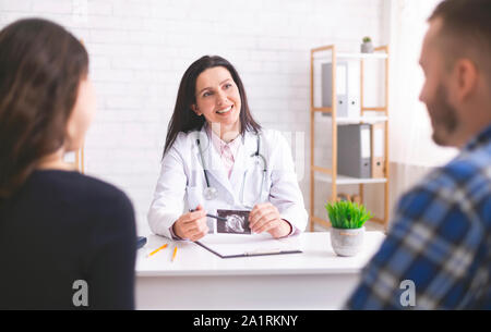 Freundliche Arzt erklären Schwangerschaft Diagnose zu junges Paar Stockfoto