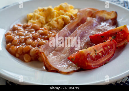 Englisches Frühstück mit gegrilltem Speck, Tomaten, Rührei und gebackene Bohnen in Tomatensoße in Spanien Stockfoto