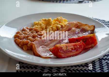 Englisches Frühstück mit gegrilltem Speck, Tomaten, Rührei und gebackene Bohnen in Tomatensoße in Spanien Stockfoto