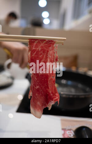 Halten Fleisch mit Essstäbchen Stockfoto