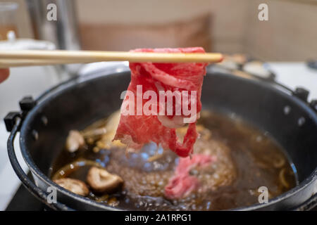 Halten Fleisch mit Essstäbchen Stockfoto