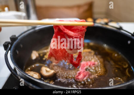 Halten Fleisch mit Essstäbchen Stockfoto