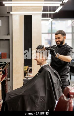 Brutaler Kerl in der modernen Friseur. Friseur Frisur macht ein Mann. Master Friseur nicht Frisur mit Haarschneider. Konzept barbershop Stockfoto