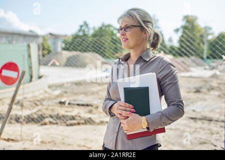 Portrait von Business reife Geschäftsfrau auf der Baustelle Instandsetzung der Straße in der Stadt, Pflasterstein Festlegung Stockfoto