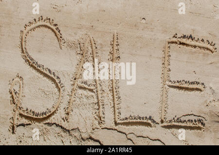 Das Wort Verkauf ist in den Sand gemalt. Strand Hintergrund. Blick von oben. Das Konzept der Sommer, Sommer kanikkuly, Urlaub, Ferien. Stockfoto
