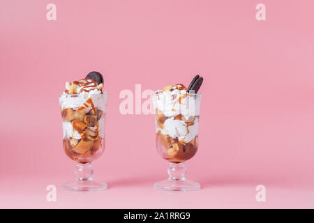 Süßes Dessert im Glas mit Keks und Schlagsahne auf Rosa bsckground, selektiver Fokus und Leerzeichen Stockfoto