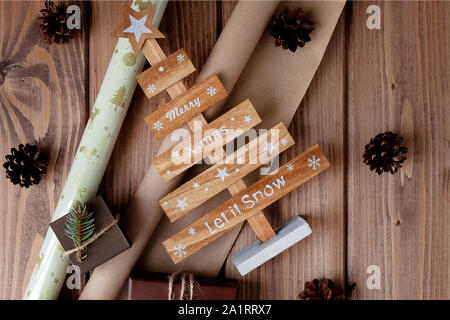 Verpackte Weihnachtsgeschenke in Handwerk Papier auf Holz- Tabelle. Prozess der Verpackung der Geschenke. Lifestyle Hintergrund. Blick von oben. Weihnachten Konzept Stockfoto