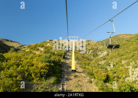 Sessellift auf dem Hügel des Berges mit blauen Himmel im Hintergrund. Sightseeing Konzept. Ausflüge auf Urlaub. Sonnigen Tag. Stockfoto