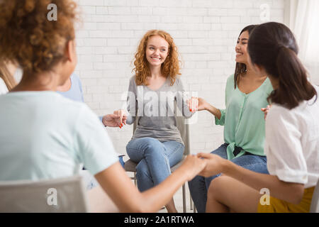 Diverse Mädchen lächelnd halten sich an den Händen sitzen innen Stockfoto