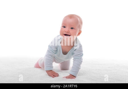 Kleines Mädchen auf einem weißen Teppich in einem hellen Raum. Stockfoto