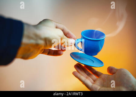 Floating blau Tasse Espresso mit Händen. First-Person anzeigen. Mock up des Segelfliegens in der Luft Tasse heißen Kaffee. Schweben Konzept Stockfoto