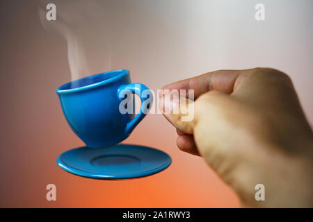 Floating blau Tasse Espresso mit Händen. First-Person anzeigen. Mock up des Segelfliegens in der Luft Tasse heißen Kaffee. Schweben Konzept Stockfoto