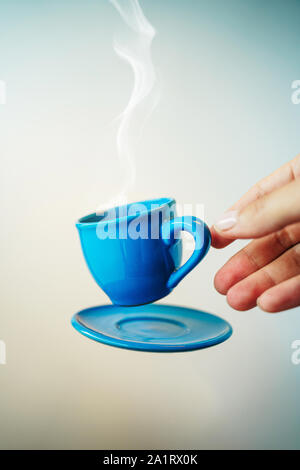 Floating blau Tasse Espresso mit Hand. Mock up des Segelfliegens in der Luft Tasse heißen Kaffee. Schweben Konzept Stockfoto