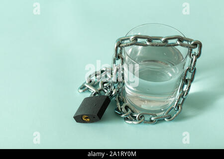 Ein Glas Wasser in einer Kette gewickelt und mit einem Vorhängeschloss. Das Konzept des Problem der kleinen Trinkwasser in der Welt. Stockfoto