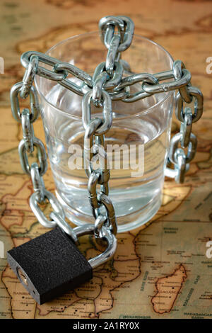 Ein Glas Wasser in einer Kette gewickelt und mit einem Vorhängeschloss. Das Konzept des Problem der kleinen Trinkwasser in der Welt. Stockfoto