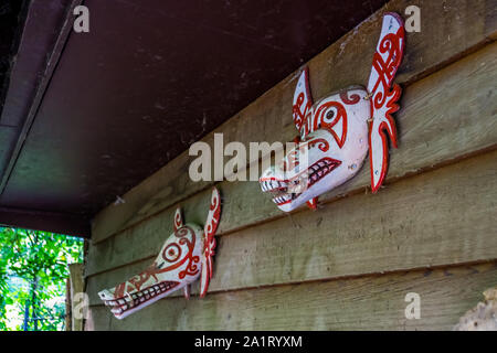 Asiatische Drachen Masken hängen an einer Holzwand, traditionellen Dekorationen Stockfoto