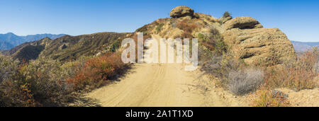 Feldweg führt entlang einer ridgeline neben massiven Geröllsteinen in der Wüste von Südkalifornien. Stockfoto