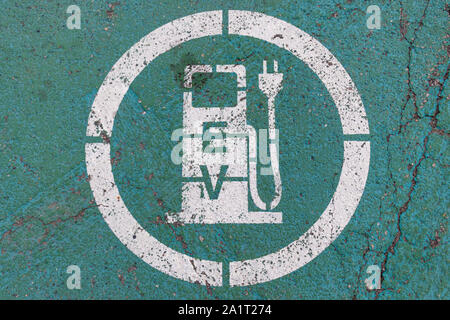 Symbol für die Ladestation für Elektrofahrzeuge (EV) auf alterndem grün lackiertem Straßenbelag. Stockfoto