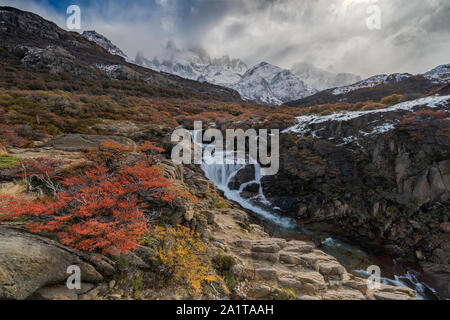 Blick auf den Mount FitzRoy mit Wasserfall und sunstar. Die bergkette wird teilweise von Wolken verdeckt. Stockfoto